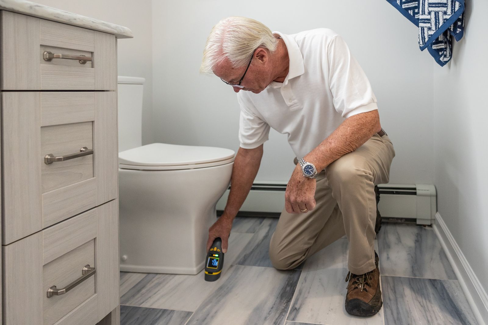 A home-services technician inspecting a bathroom with a handheld meter
