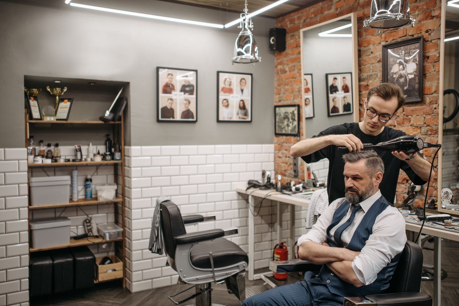 A barber blow-drying a client's hair in a barbershop