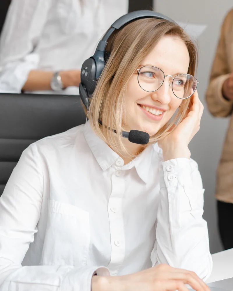 Assistante du service client souriante, avec un casque, travaillant sur un ordinateur portable
